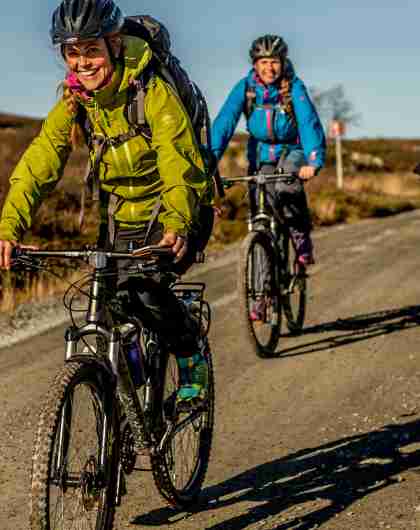 Three people cycling at a dirt road on the Hardangervidda mountain plateau in Eastern Norway