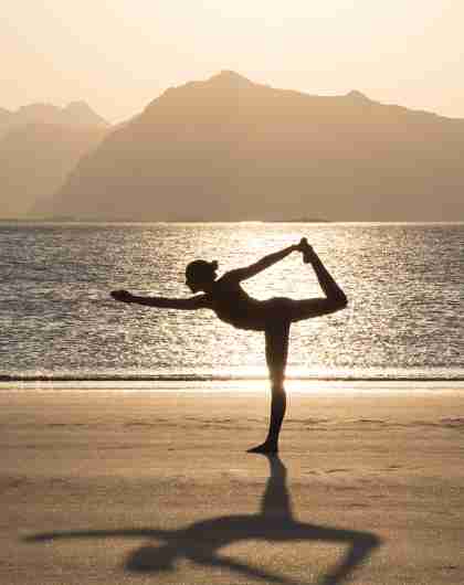 A women practicing yoga in silence on the beach in Lofoten, Northern Norway