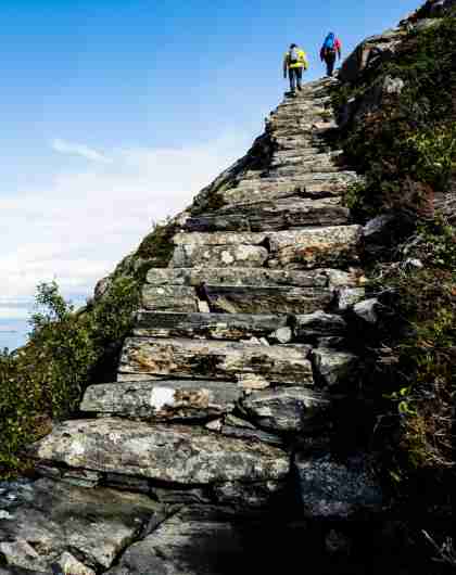To mennesker klatrer opp steintrappa Midsundtrappene mot Rørsethornet nær Molde på Vestlandet