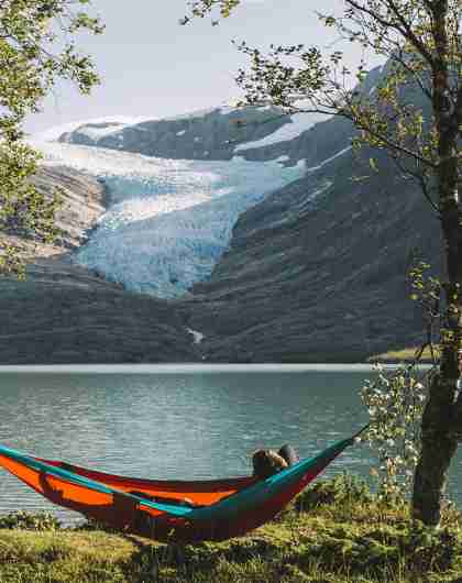 People in hammocks in front of the Svartisen glacier in Helgeland, Northern Norway