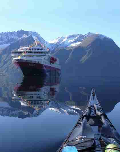 View of the Hurtigruten ship MS Nordlys from a kayak at Hjørundfjorden in Fjord Norway