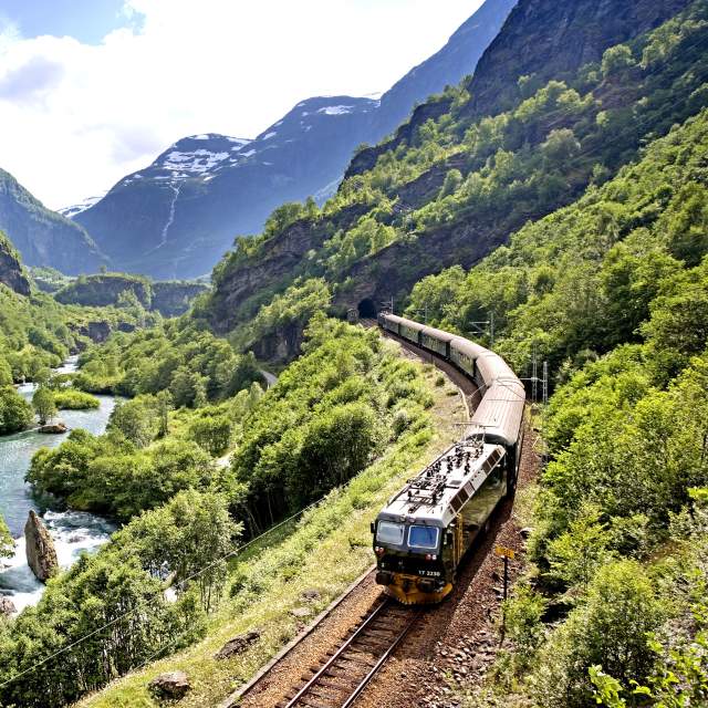 The Flåm railway going through the landscape of green hills and spectacular mountains in Fjord Norway