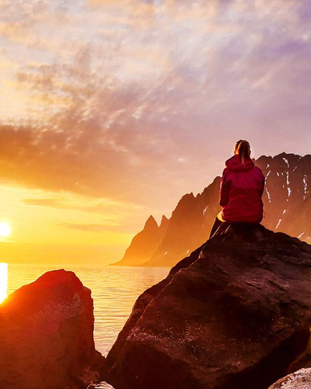 A person watching the midnight sun at Senja in Northern Norway