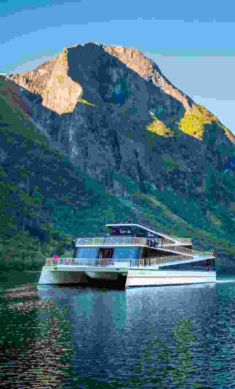 The ship Vision of the Fjords sailing between high mountains on a sunny summer day in Fjord Norway