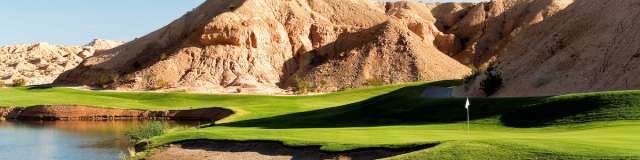 Breathtaking view of Oasis Canyons Golf Course by the water with a mountain hill in the backdrop in Mesquite, Nevada.