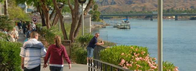 A couple walking down the Laughlin River Walk holding hands.