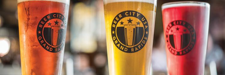 Copy of Beer City Pint Glasses Three pint glasses that read 'Beer City USA Grand Rapids' filled with different beers.