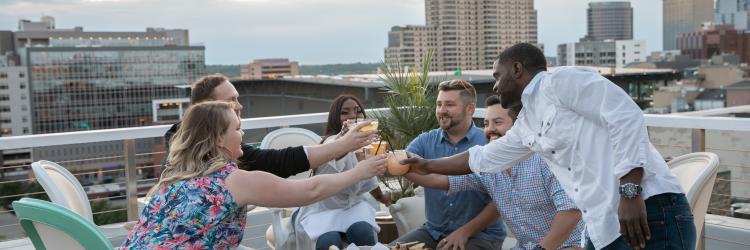 Friends enjoying cocktails and cheers-ing on rooftop