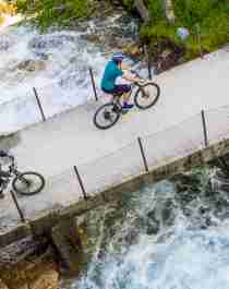 Two cyclists crossing a bridge on the river on the Rallarvegen, Fjord Norway