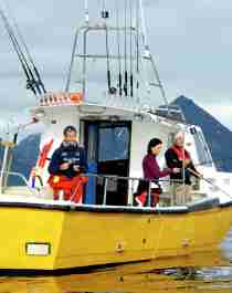 Three people sea fishing from a fishing boat at Kattfjorden in Northern Norway