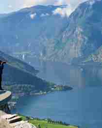 A man standing at a viewpoint taking pictures of the Aurlandsfjord