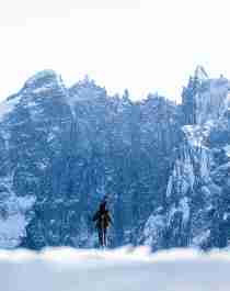 En person på ski ser på Trollveggen dekket av snø