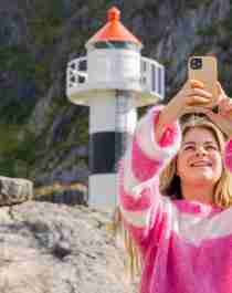 Woman taking a selfie with a lighthouse in Vesterålen, Northern Norway