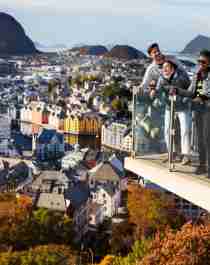 Three people standing at a viewpoint above the city of Ålesund in Fjord Norway
