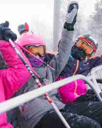 Three happy girls sitting in a ski lift in Geilo ski resort, Eastern Norway
