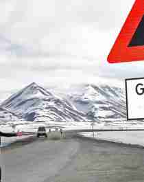 A marathon runner passing a polar bear warning sign in Spitsbergen in Svalbard