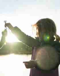 Liten jente holder opp fisk foran innlandsvann på Blefjell