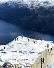 Two men standing on Preikestolen, the Pulpit Rock, looking out over Lysefjord