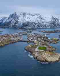 A football field on an island in Lofoten with snow-clad mountains in the horizon