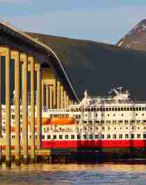 Hurtigruten sailing under a bridge in Tromsø