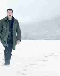 A man with a gun walking in the snow. From the movie poster for Jo Nesbø’s The Snowman.