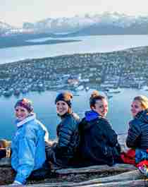 En gruppe jenter sitter og nyter utsikten over Tromsø by