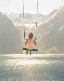 A girl on a the world’s most beautiful swing in Trandal by the Hjørundfjord in Fjord Norway