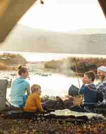 Familie på fire sitter ved et bål i Oppdal