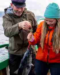 A woman and a man on a boat at sea just caught a fish