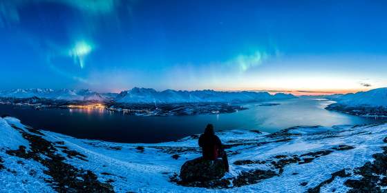 En person ser på nordlyset over Lyngsalpan