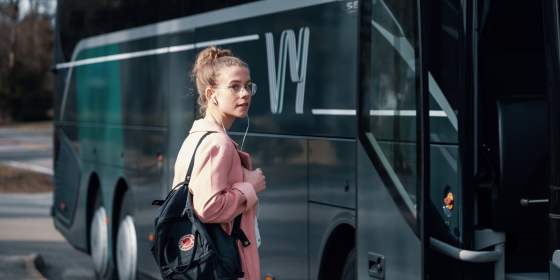 En buss fra Vy express kjører på en vei gjennom et grønt landskap