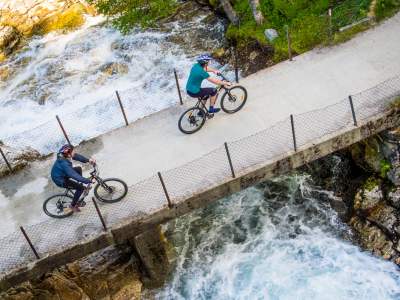 Two cyclists crossing a bridge on the river on the Rallarvegen, Fjord Norway