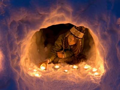 A girl lights a candle in a snow igloo in Trysil in Eastern Norway