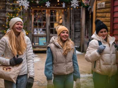 Three girls walking between the Christmassy wooden houses in Bergen, Fjord Norway