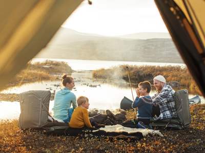 Family on four sitting by the campfire beside the tent in Oppdal, Trøndelag