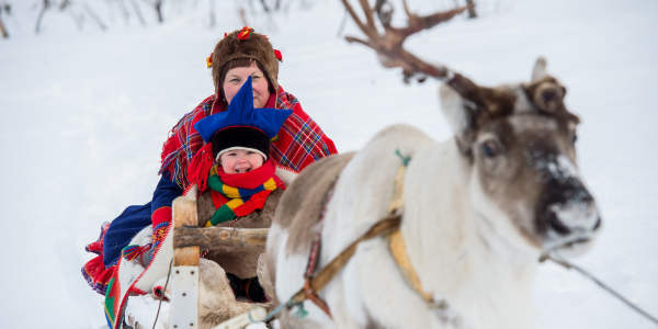 A woman and a little boy riding a reindeer sledge in Finnmark in Northern Norway