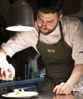 Chef Skyler Milner preparing dish at Bro restaurant in Ålesund