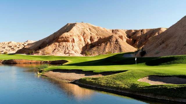 Breathtaking view of Oasis Canyons Golf Course by the water with a mountain hill in the backdrop in Mesquite, Nevada.