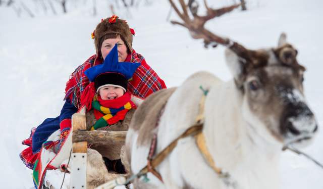 A woman and a little boy riding a reindeer sledge in Finnmark in Northern Norway