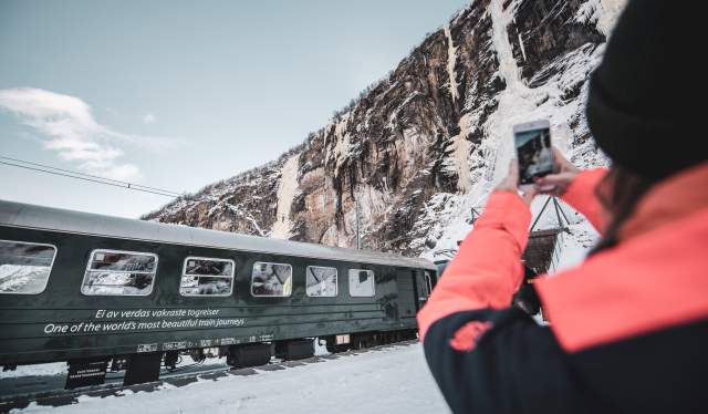 A woman taking a picture of the Flåmsbana train