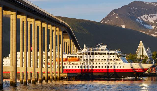 Hurtigruten sailing under a bridge in Tromsø