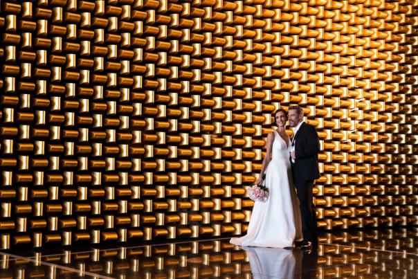 A couple standing in front of a wall for a wedding photo.