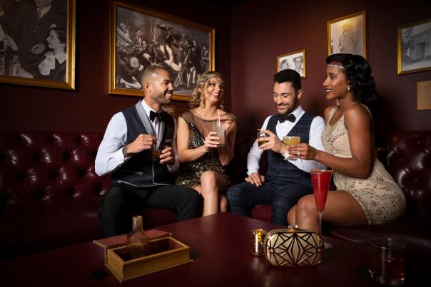 A group of people enjoying themselves with a drink at The Underground Speakeasy inside of the Mob Museum.