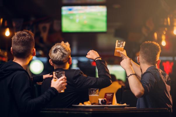 A table of excited sports fan cheering on their team with beers in hand!