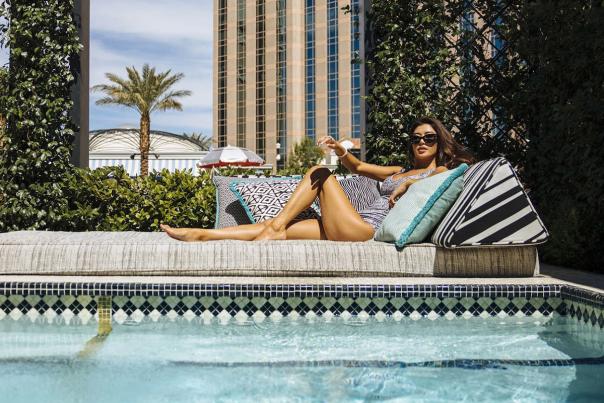 A woman laying down on an outdoor couch poolside.