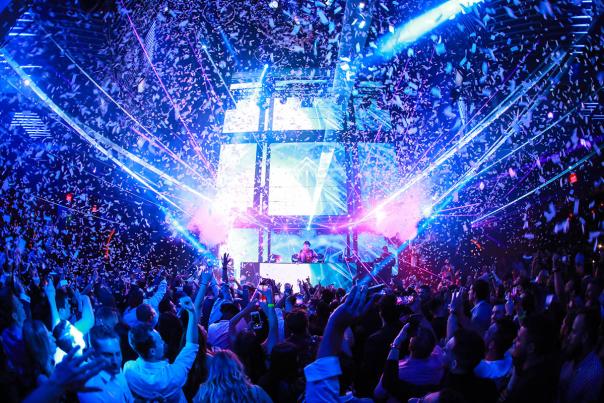 People dancing in a nightclub with laser lights and confetti falling from the ceiling