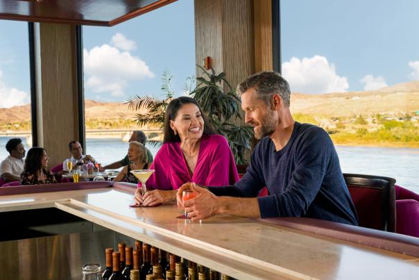 A couple enjoying some delicious cocktails in Laughlin with the beautiful Colorado river behind them.