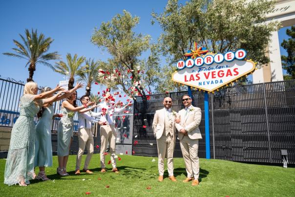 Couple celebrating wedding in front of the iconic "Married in Fabulous Las Vegas" sign at Chapel of the Flowers