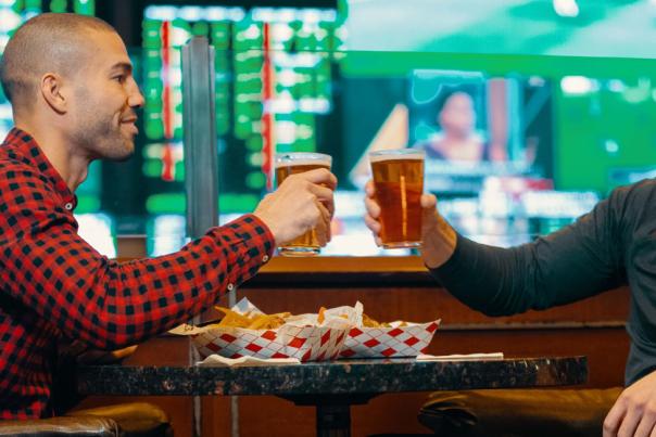 Two men cheersing a beer at a bar