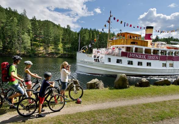 A family cycling past M/S Henrik Ibsen on the Telemark Canal
